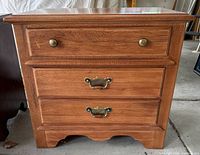 Front view showing three drawers with brass-tone hardware
