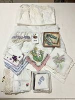Overview showing folded full slip, displayed half slip with lace hem, three garters, and stacks of vintage handkerchiefs