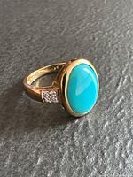 Side view of ring showing turquoise cabochon, gold bezel and diamond shoulder accents