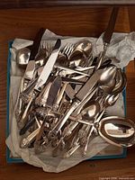 Box filled with mixed Community Plate flatware pieces