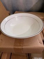 white porcelain rimmed soup bowl with silver trim on top of shipping box