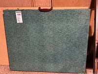 Front view of folded green table showing carry handle
