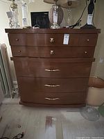 Front view of mid-century wooden dresser showing drawer configuration and brass hardware