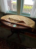 Oval wooden table with folded tablecloth displayed