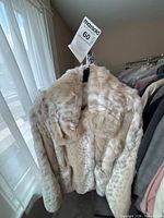 Cream snow-leopard faux fur jacket on hanger