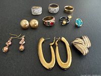 Group shot of all five rings and three pairs of earrings on black background
