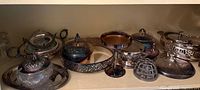 Shelf of assorted silver-plated lidded dishes, trays, and decorative pieces