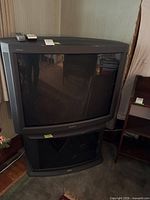 Front view of Sony Trinitron CRT TV on stand with two remotes on top