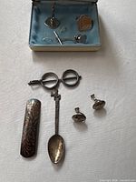 all sterling items laid out including cufflinks in case, tie pin, earrings, hair clip, spoon