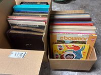 Two cardboard boxes filled with assorted vinyl records, jackets visible