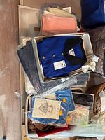 Overhead view of boxed Kasper jacket, packaged scarves, folded tops