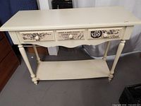 front view of off-white console table showing drawers and lower shelf