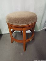 full view of one wood swivel stool showing frame and cushion