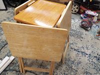 Stacked wooden folding tray tables showing varied finishes