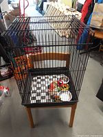 Full view of bird cage on chair showing wire construction and base