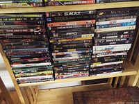 Two tall stacks and a top shelf row of assorted DVD cases on wooden shelving