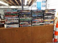 Wide view of approximately 75 DVDs stacked on table