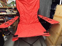 Front view of red folding camping chair showing seat, back and armrests