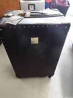 Front view of black rivet-trimmed rolling suitcase