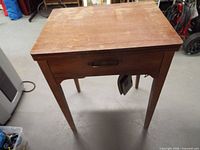 Closed wooden sewing cabinet with drawer and hanging foot pedal