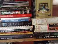 Wide view of stacked cookbooks on shelf showing multiple titles