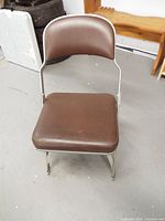 Front view of brown vinyl padded metal folding chair fully opened