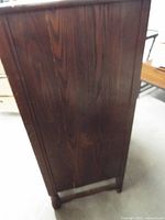 Side view of dark stained dresser showing wood grain and feet
