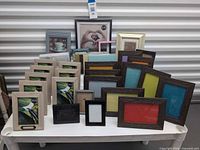 Group shot showing taupe wood 3.5x5 frames, dark faux woodgrain 5x7 frames with coloured inserts, grey 5x7 frames, sealed 8x10 frame, pink frame and misc pieces
