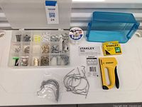 Full lot overview showing stapler, staples box, organizer with hardware, blue bin, monofilament spool, bag of hooks