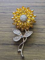 Front view showing full brooch, amber petals, clear center, rhinestone leaf, gold-tone stem