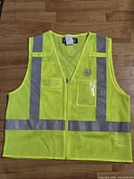Front view of neon yellow safety vest laying flat showing reflective strips and pockets