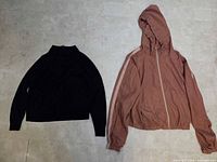 Black sweater and pink jacket side by side on floor