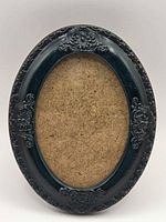 Front view of oval black resin frame with floral relief