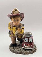 Front view showing child firefighter holding hose and bucket, toy fire truck, helmet No. 75 visible