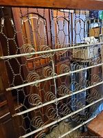 metal coil spring frame leaning against armoire, armoire panels visible