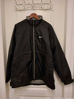 Front view of black Nike full-zip jacket on hanger