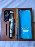 Micrometer in open wooden case showing blue Tesa sleeve