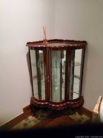 Corner mahogany curio cabinet closed, showing curved front and glass panels