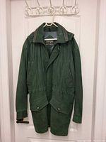 Front view of emerald green hooded leather jacket showing pockets and storm flap