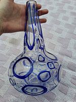 Vase held in hand showing scale and blue ring pattern on bulbous body