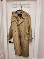 Front view of beige trench coat on hanger showing double-breasted design and epaulets