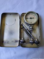 Open tin showing gauge, probes, tools