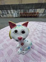 Front view of ceramic cat coin bank showing hand-painted floral designs and facial details