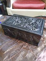 Top and side view of black carved box on fabric surface