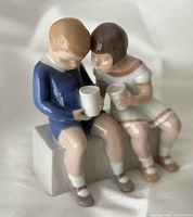 Front view of porcelain figurine showing two children holding cups