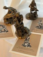 Three bronze-tone figurines with matching collector cards