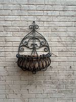 Full view of wrought iron wall planter on brick wall