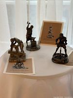 All three pewter figurines with their booklets displayed on table