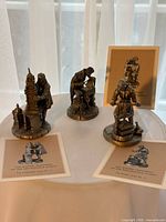 Three Franklin Mint figurines with their ID cards displayed on table