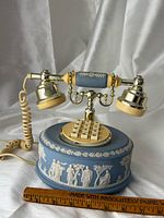 Front view showing keypad, cradle, relief figures, cord, and ruler for scale